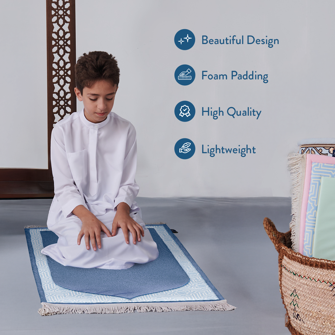 Young boy sitting on junior padded prayer mat in blue design from urban rugs uk