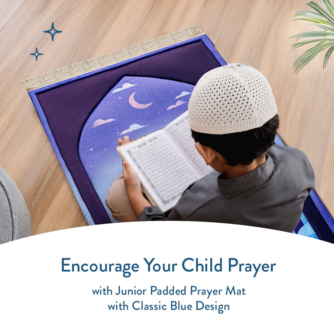 Young boy reading Quran while sitting on junior padded prayer mat with classic blue mosque design by urban rugs uk